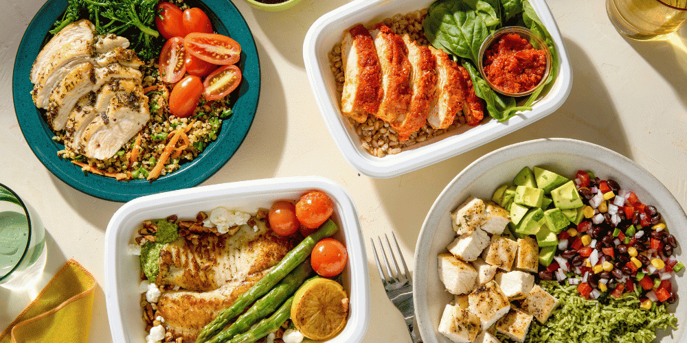 Four chef-prepared CookUnity meals featuring grilled chicken, baked fish with asparagus, and fresh grain bowls with vegetables