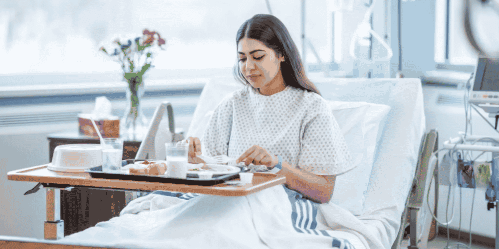 Hospital patient eating a meal in bed from a tray in a bright hospital room