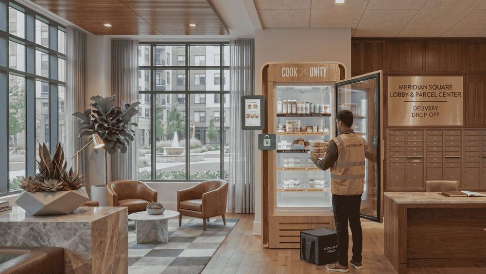 CookUnity delivery staff member restocking a smart fridge in a luxury apartment building lobby with fresh meals, with no property team involvement required